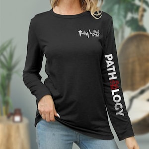 May include: Black long-sleeve shirt with a white medical symbol and heartbeat graphic on the front and the word "PATHOLOGY" in white with a red symbol on the right sleeve.