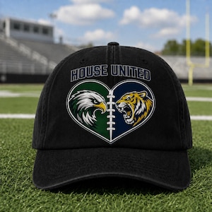 May include: A black baseball cap featuring a graphic of a heart split by football laces. The left side shows a green and white eagle, and the right side shows a yellow and black tiger. The text HOUSE UNITED is printed in blue above the heart.