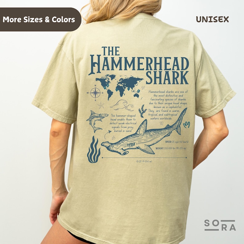 K&ouml;nnte beinhalten: Ein hellgr&uuml;nes Unisex-T-Shirt mit einem Grafikdruck eines Hammerhais und einer Weltkarte. Der Text "THE HAMMERHEAD SHARK" ist in Blau auf dem Shirt gedruckt. Das Shirt enth&auml;lt auch Informationen &uuml;ber den Hammerhai, wie z. B. seine Geschwindigkeit und sein Gewicht.