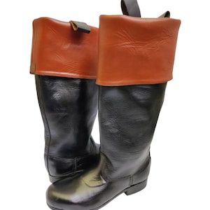 May include: A pair of black leather boots with brown leather tops. The boots have a pointed toe and a low heel.