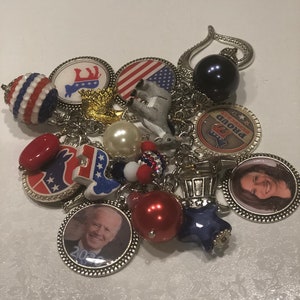May include: A charm bracelet with various political themed charms, including a donkey, an elephant, a star, a red, white, and blue bead, and a charm with the image of Joe Biden and Kamala Harris. The bracelet also includes a charm with the text "Proud Democrat".