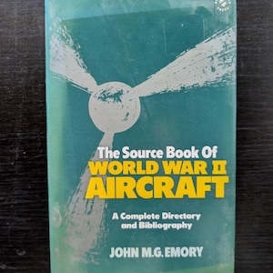 Può includere: Un libro d'epoca intitolato "The Source Book Of World War II Aircraft" con una copertina verde acqua. Il titolo è in giallo e bianco, con un grafico di un'elica. L'autore è John M.G. Emory.