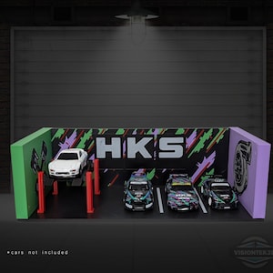 May include: A diorama featuring a white car on a lift and three other model cars. The backdrop has the text "HKS" and a graphic design. The diorama is green, black, and purple.