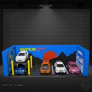 May include: A blue and yellow diorama with the text "WRX STI" and a Subaru logo. The diorama features a car lift with two model cars, and three additional model cars parked on a black surface. The text "* cars not included" is at the bottom.