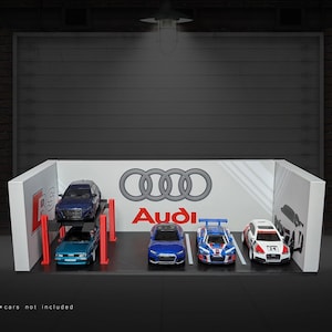 May include: A white display case featuring the Audi logo and four miniature cars inside. The cars are a blue Audi RS4, a blue Audi R8, a white Audi R8, and a red Audi R8. The cars are on a white platform with red supports.