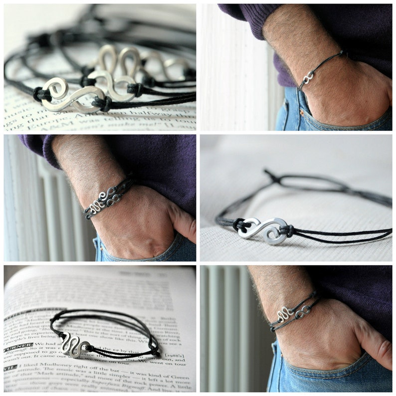 May include: A black leather bracelet with a silver infinity symbol charm. The bracelet is shown on a person's wrist.