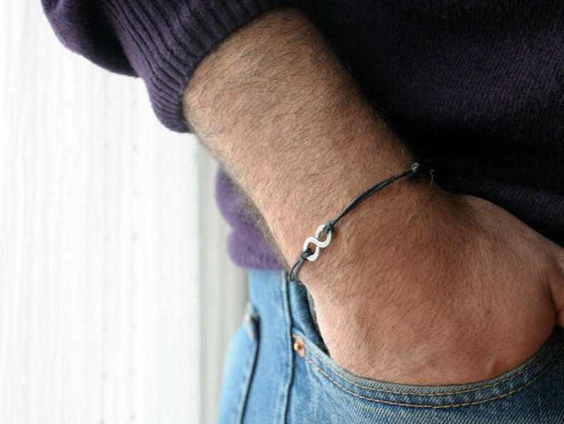May include: A black cord bracelet with a silver infinity symbol charm.