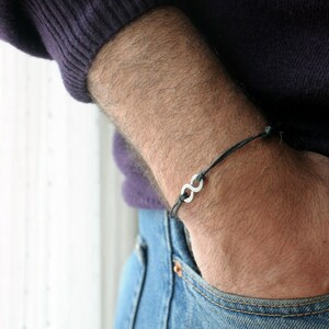 May include: A black cord bracelet with a silver infinity symbol charm.