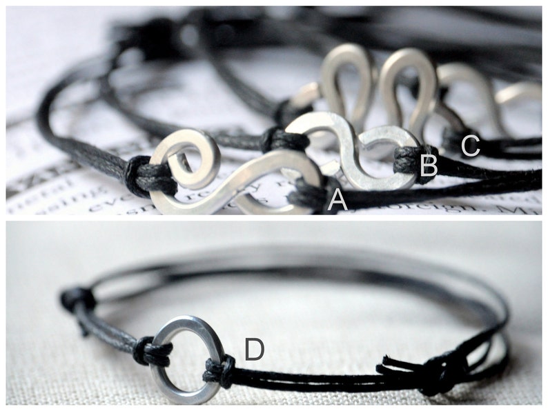 May include: Two black cord bracelets with silver metal charms. One bracelet has a charm shaped like a treble clef, the other has a round charm.