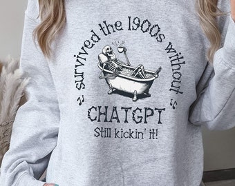 Pode incluir: Uma camisa de moletom cinza com um esqueleto em uma banheira e o texto "Eu sobrevivi aos anos 1900 sem ChatGPT. Ainda estou aqui!"