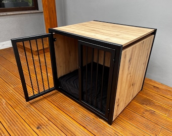 Könnte beinhalten: Ein Hunde-Käfig aus Holz mit einem schwarzen Metallrahmen und einem schwarzen Stoffbett im Inneren. Der Käfig hat eine Tür, die offen ist.