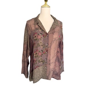 May include: A long-sleeved button-down shirt in muted mauve and olive tones, featuring a patchwork design with floral patterns, intricate botanical line drawings, and textured geometric prints across the front panels and collar.