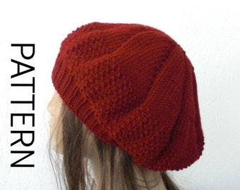 May include: A red knitted beret with a textured pattern. The beret is worn on a mannequin with long brown hair.