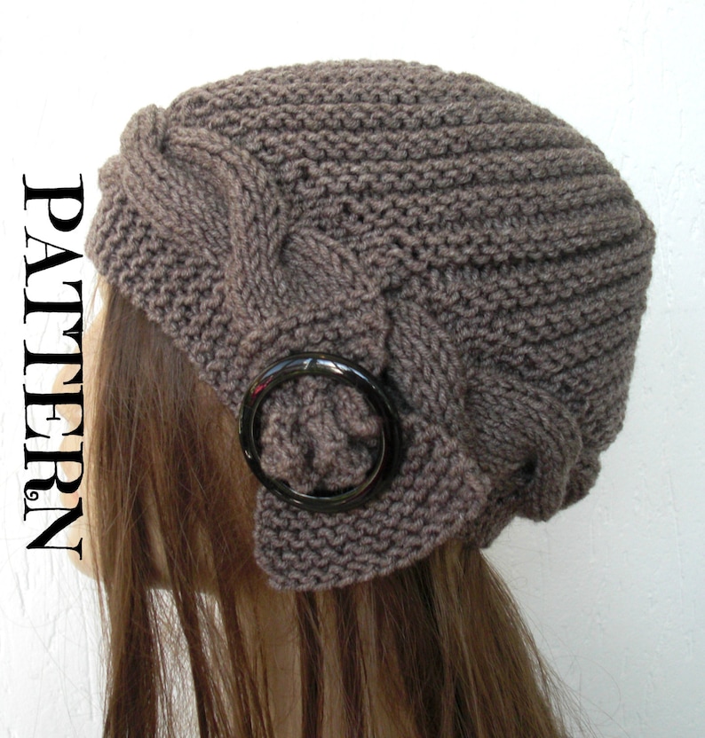 May include: A brown knitted hat with a cable knit pattern and a black metal ring accent. The hat is worn on a mannequin with long brown hair.