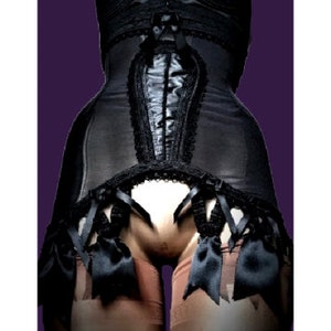 May include: Black satin corset with lace trim and black ribbon accents. The corset has a front closure with a series of hooks and eyes. The corset is worn with black garters and stockings.
