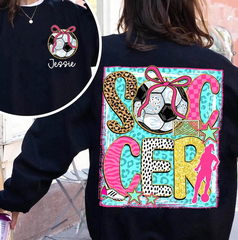 Op de afbeelding: Een marineblauw sweatshirt met een voetbalafbeelding met een roze strik en het woord "Jessie" op de voorkant. De achterkant toont het woord "SOCCER" met een voetbal, een silhouet van een speler en steraccenten.