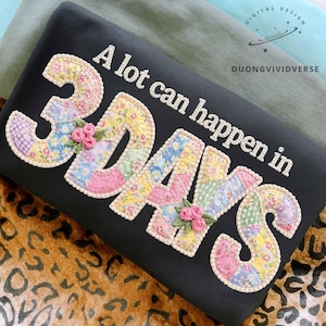Puede incluir: Sudadera negra con la frase blanca "A lot can happen in 3 DAYS". Los números y letras son de estilo patchwork con estampados florales y pequeños detalles de flores rosas. El diseño está sobre un fondo negro.