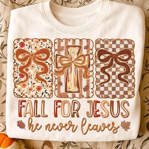 May include: Cream-colored sweatshirt featuring three decorative panels with bows and a cross design. The text "FALL FOR JESUS he never leaves" is printed in brown and orange. The panels have floral, striped, and checkered patterns.
