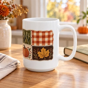 Puede incluir: Una taza de cerámica blanca con un diseño de patchwork de cuatro paneles rectangulares. Los paneles muestran una rama de olivo sobre verde, un patrón de cuadros naranja y blanco, una calabaza sobre fondo crema y una hoja de arce amarilla.