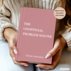 Może przedstawiać: Książka w twardej oprawie w kolorze przybrudzonego różu z białym napisem THE UNOFFICIAL PROBLEM SOLVER oraz Olivia Johnson. Okrągła beżowa odznaka w prawym górnym rogu zawiera tekst MULTIPLE COLORS OPTIONS ciemnobrązową czcionką.