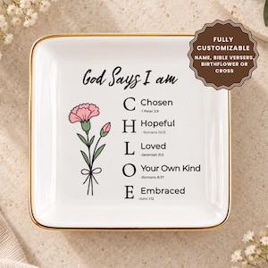 Peut inclure: Un vide-poche carré en céramique blanche avec un bord doré. Le centre présente une illustration d'œillet rose et le texte God Says I Am, suivi du nom CHLOE avec les mots correspondants Chosen, Hopeful, Loved, Your Own Kind et Embraced.