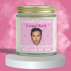 May include: A white candle jar with a pink label that says "I couldn't get you Cooper Koch so I got you something that smells like him". The label has a picture of a man and pink hearts.