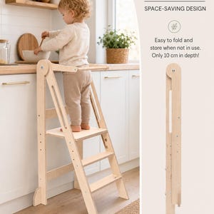 Pode incluir: Uma torre de aprendizagem de madeira clara com um design dobrável que economiza espaço. A estrutura possui uma plataforma e degraus para elevação. O texto na imagem diz: FOLDABLE, SPACE-SAVING DESIGN, Easy to fold and store when not in use. Only 10 cm in depth!