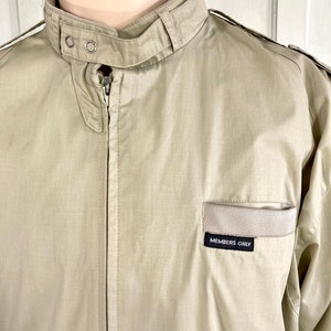 May include: A beige Members Only jacket with a zipper closure and a small patch on the chest that reads "Members Only".