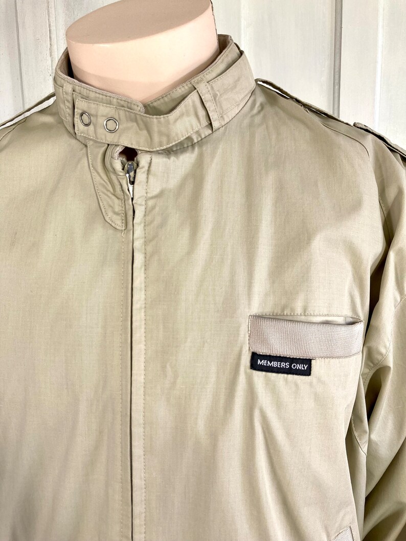 May include: A beige Members Only jacket with a zipper closure and a small patch on the chest that reads "Members Only".
