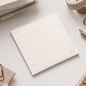 May include: A square, off-white paper notepad featuring a printed grid calendar layout with thirty numbered squares. The top left corner displays the word GOAL, while the bottom left corner displays the word REWARD. The number 30 is printed in the bottom right corner.