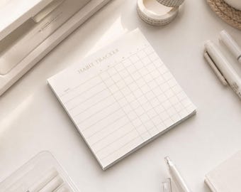 Könnte beinhalten: Ein quadratischer Habit-Tracker-Block aus Papier mit cremefarbenem Hintergrund und dünnen grauen Gitterlinien. Oben auf der Seite steht der Text HABIT TRACKER in einer einfachen Schriftart, mit Spalten für Wochentage und Zeilen für tägliche Aufgaben.