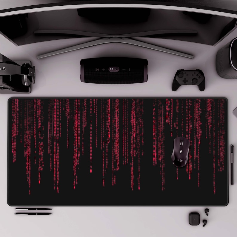 K&ouml;nnte beinhalten: Eine schwarze Gaming-Mausmatte mit einem roten Matrix-Code-Design. Die Mausmatte liegt auf einer wei&szlig;en Oberfl&auml;che mit einem schwarzen Computermonitor, einem schwarzen Lautsprecher, einem schwarzen kabellosen Controller und einer schwarzen kabellosen Maus.