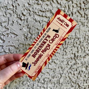 Pode incluir: Um bilhete de estilo vintage com um esquema de cores vermelho e creme. O bilhete diz "Bobinsky's Jumping Mouse Circus" com um chap&eacute;u alto e um bigode. O bilhete tamb&eacute;m diz "Admit One" e "Fila 7, Assento 01".