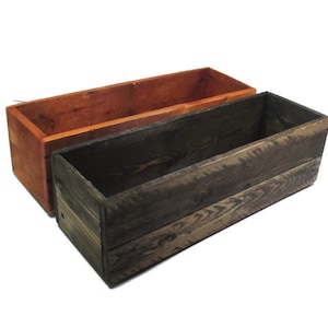 May include: Two wooden planter boxes, one stained a dark brown and the other a reddish brown. Both boxes are rectangular and have a rustic appearance.