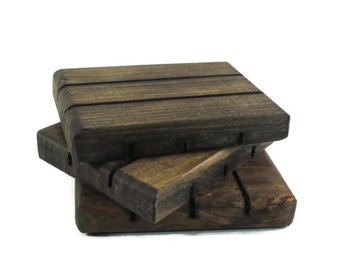 May include: Two stacked wooden soap dishes with a dark brown finish. The top dish has three grooves and the bottom dish has four grooves.
