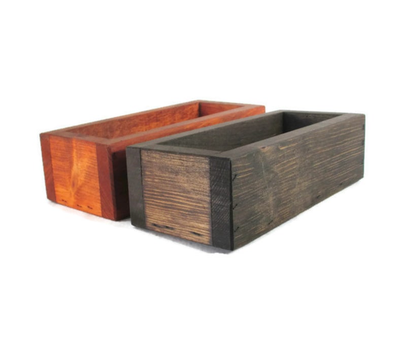 May include: Two wooden boxes, one stained a dark brown and the other a reddish brown. Both boxes are rectangular and have a simple design.