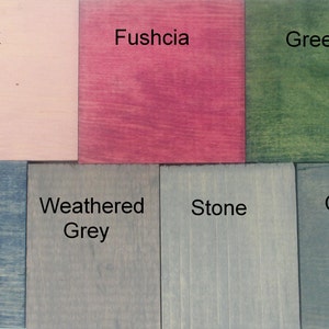 May include: A set of eight wood samples stained in different colors, including pink, fuschia, green, blue, weathered grey, stone, and coal.