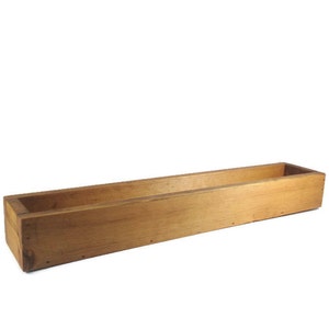 May include: A long, rectangular wooden planter box with a natural wood finish. The planter is empty and ready to be filled with plants.