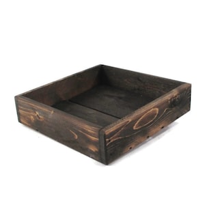 May include: A dark brown wooden tray with a square shape. The tray is made of unfinished wood and has a rustic look.