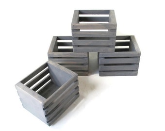 May include: Four gray wooden crates stacked on top of each other. The crates are made of unfinished wood and have a rustic look.