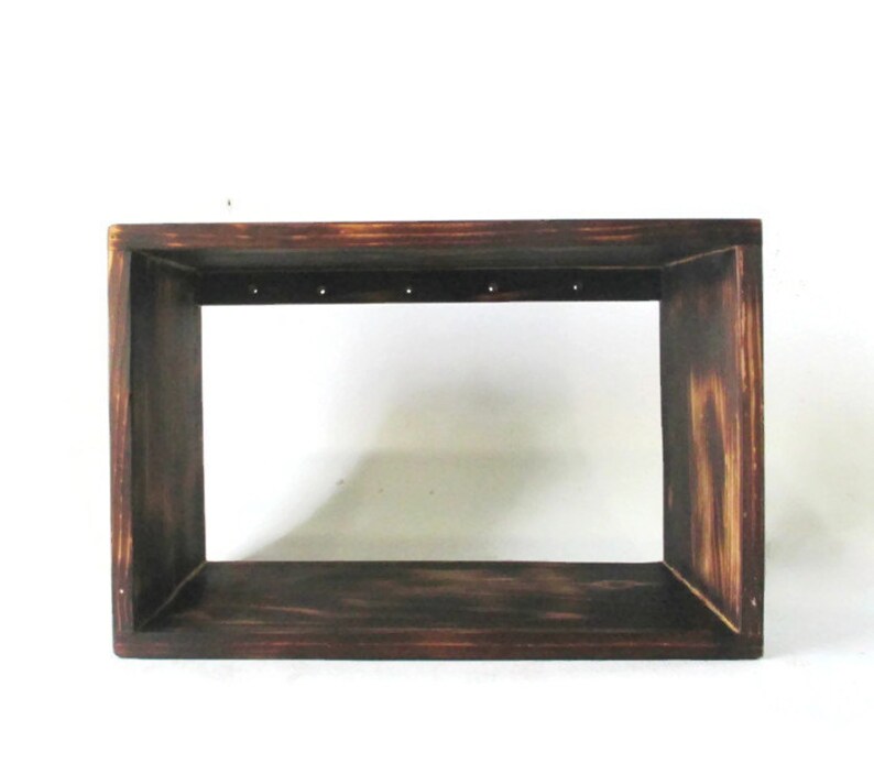 May include: A dark brown wooden frame with a rectangular opening. The frame has a distressed look and is made of unfinished wood.