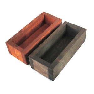 May include: Two wooden rectangular boxes with open tops. The box on the left is a reddish brown color and the box on the right is a dark brown color.