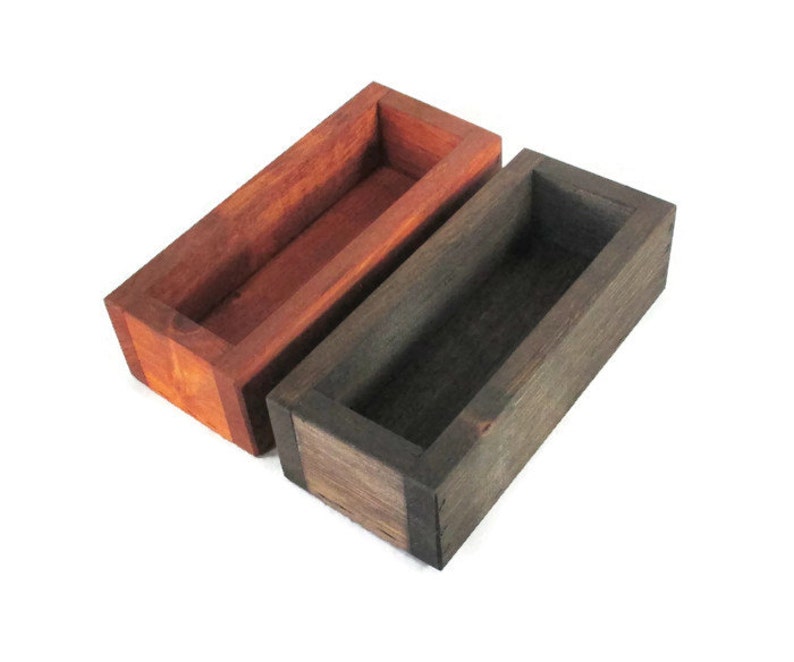 May include: Two wooden rectangular boxes with open tops. The box on the left is a reddish brown color and the box on the right is a dark brown color.