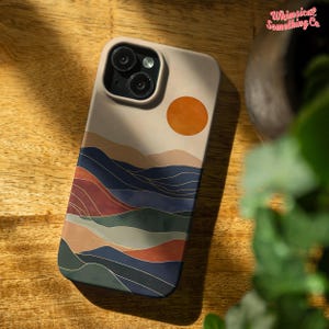 Puede incluir: Una funda para tel&eacute;fono con un dise&ntilde;o abstracto colorido que representa una puesta de sol sobre una cordillera. La funda es beige con un dise&ntilde;o azul, verde, rojo y naranja.