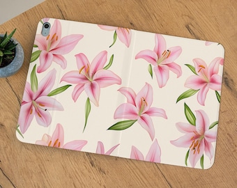 May include: A cream-colored tablet case featuring a repeating pattern of pink lilies with green leaves. The lilies have yellow stamens and are scattered across the surface. The text "Whimsical Something Co" is in the upper right corner.