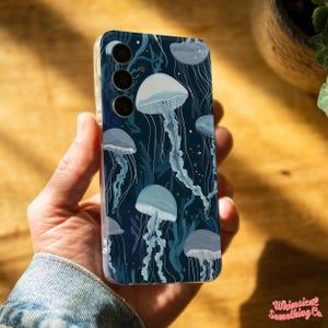 May include: A clear phone case with a dark blue background and a pattern of white jellyfish. The case has a camera cutout with three circles.