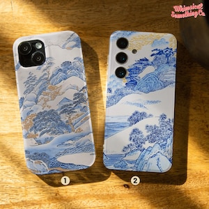 Könnte beinhalten: Zwei Handyhüllen mit einem japanisch inspirierten Design in Blau und Weiß. Die Hüllen liegen auf einer Holzoberfläche. Die Hülle links ist für ein iPhone und die Hülle rechts für ein Samsung-Handy.