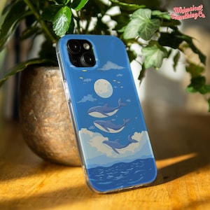 May include: A blue phone case with a design of three whales swimming under a full moon. The case has a clear border and the text "Whimsical Something Co." is visible in the upper right corner.
