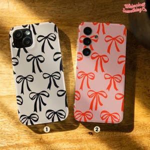 May include: Two phone cases featuring a bow pattern. The case on the left is white with black bows. The case on the right is pink with red bows. Both cases have a camera cutout.