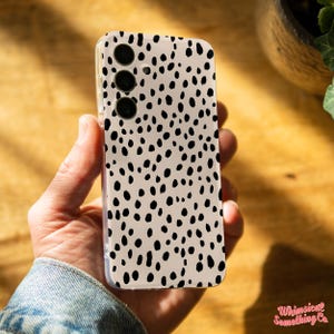 May include: A clear phone case with a black and white dalmatian print design. The case has a cutout for the camera lens.